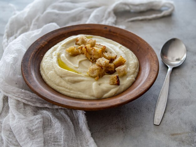 Foto sopa de alcachofra de jerusalém e croutons. sopa de creme vegan em uma tigela de cerâmica. fechar-se. copie o espaço.