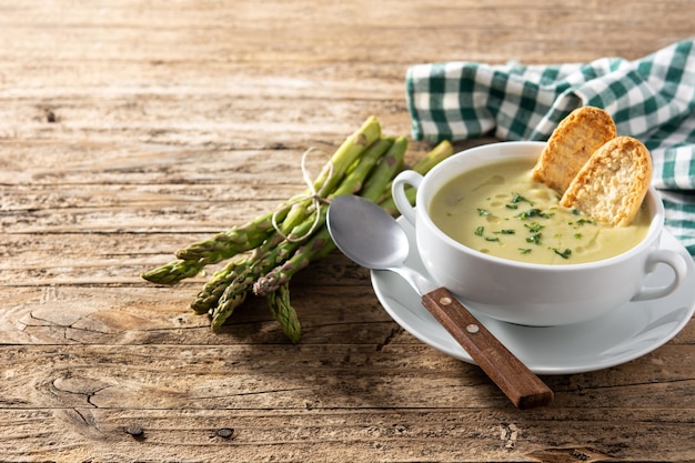 Sopa de aspargos verdes frescos em uma tigela na mesa de madeira.