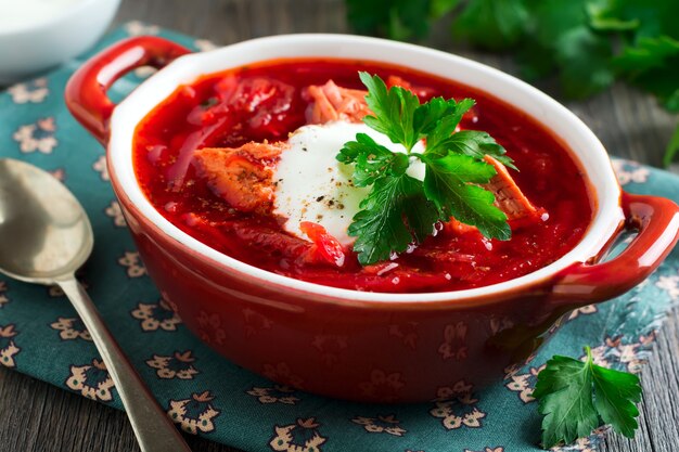 Sopa de beterraba com carne, creme de leite e salsa em tigela de cerâmica marrom