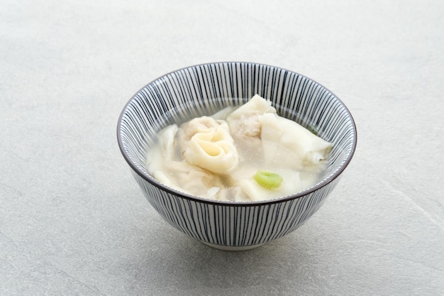 Sopa de bolinho de sopa de Wonton gostoso ou Pangsit Kuah servido em foco seletivo de tigela