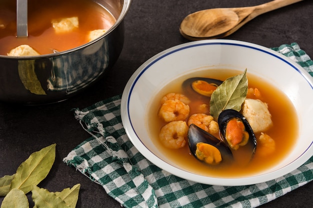 Sopa de bouillabaisse francês em chapa branca na superfície preta