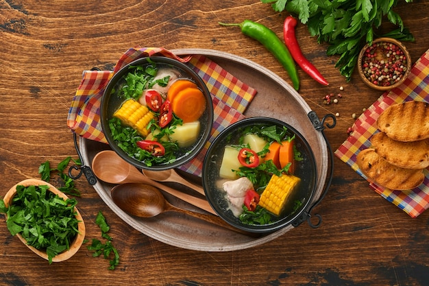 Sopa de carne chilena com pampkin, milho, coentro fresco e batatas no fundo da velha mesa de madeira. Cazuela. Comida latino-americana.