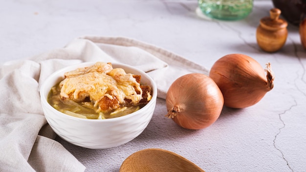 Sopa de cebola caseira com croutons e queijo em uma tigela na bandeira da mesa