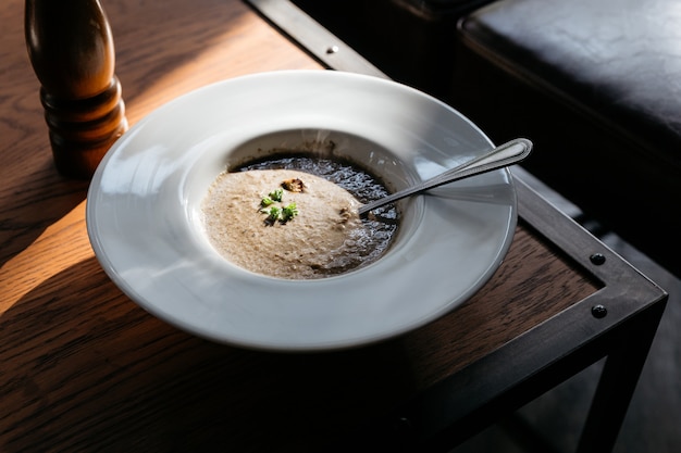 Sopa de cogumelo com grouton na placa branca com luz solar na tabela de madeira.