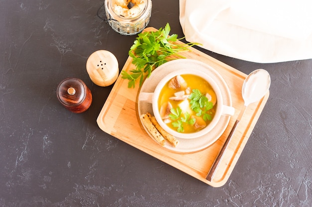 Sopa de cogumelos brancos frescos em uma tigela para sopa com ervas. em um suporte de madeira. vista do topo.