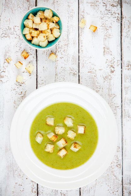 Sopa de creme caseira com brócolis e croutons em fundo de madeira