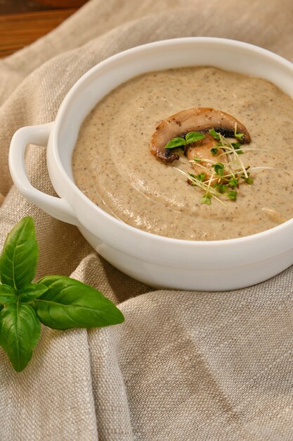 Foto sopa de creme caseira com champignon de cogumelos em tigela branca, sobre fundo rústico, estilo vintage