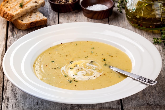 Sopa de creme de abobrinha caseira em chapa branca sobre fundo de madeira