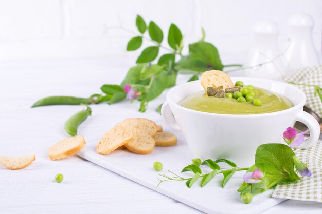 Sopa de creme de ervilhas verdes com croutons em uma tigela branca