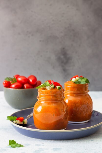 Sopa de creme de tomate frio caseiro de verão em potes de vidro