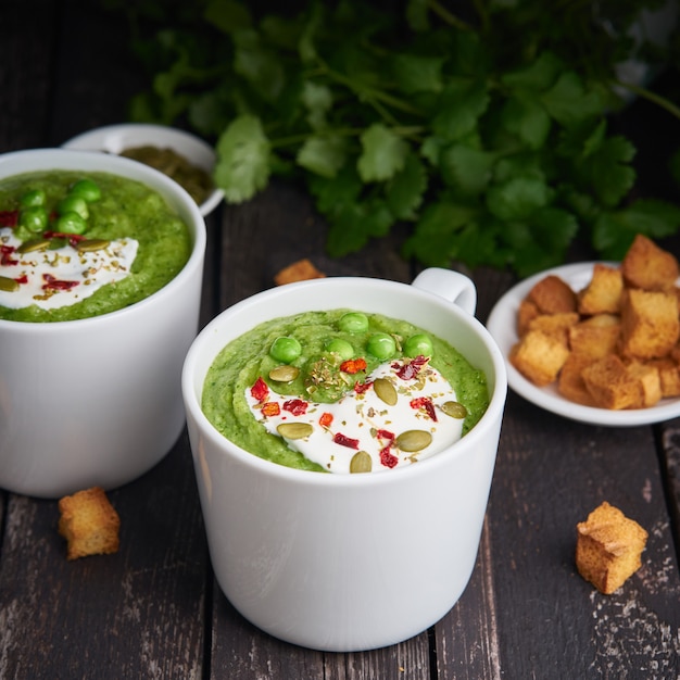 Sopa de creme dos brócolis no fundo de madeira escuro. Puré verde vegetal em dois grandes copo branco.