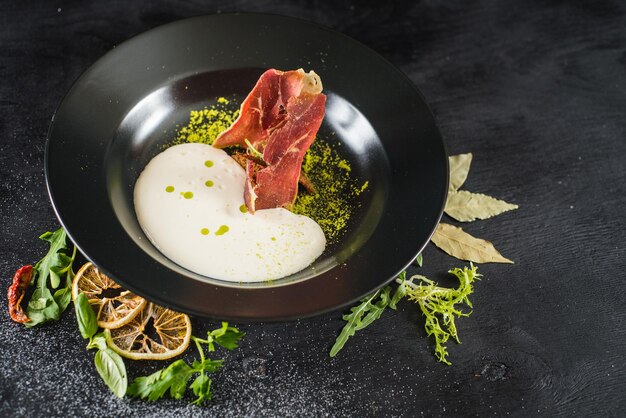 Sopa de creme saborosa com presunto seco e especiarias em fundo preto