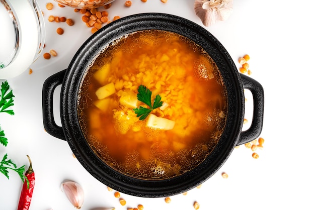 Sopa de ervilha em um fundo branco. Sopa de ervilha em uma panela preta. Salsa, pão. Foto de alta qualidade