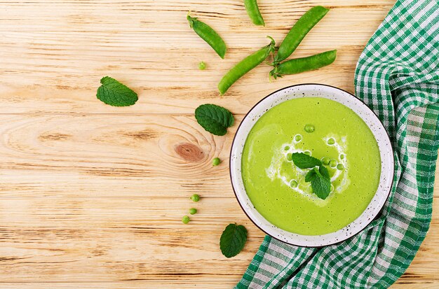 Sopa de ervilha verde em tigela na mesa de madeira