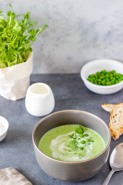 Sopa de ervilha verde sobre uma mesa cinza. Alimentação saudável. Comida vegetariana. Receita. Dieta.