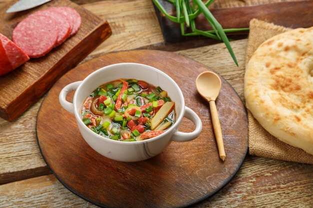 Sopa de feijão de cozinha judaica cholit em um suporte redondo perto de ingredientes de pão e uma colher de pau