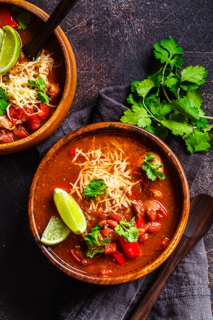 Sopa de feijão mexicana tradicional com carne e queijo em uma tigela de madeira