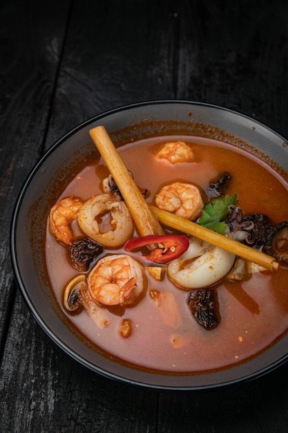 Sopa de frutos do mar com frutos do mar e molhos em mesa de madeira escura