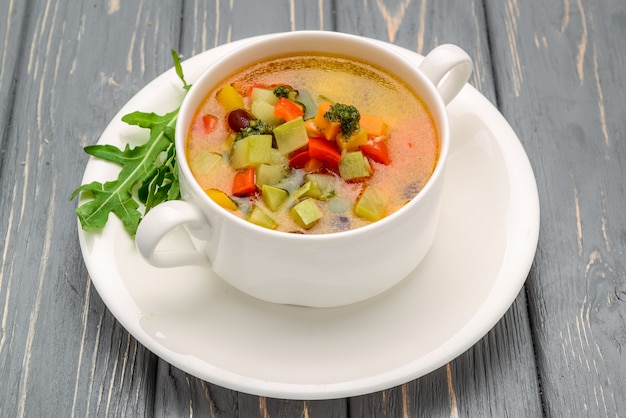 Sopa de galinha com legumes. Na mesa de madeira