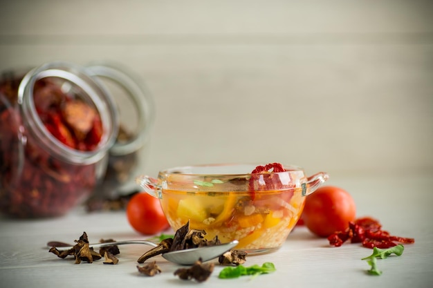 Sopa de legumes com cogumelos secos tomates secos em uma tigela sobre a mesa