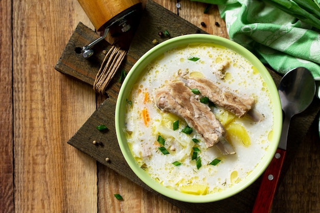 Sopa de legumes com creme de leite de repolho e costelas de carne em uma mesa de madeira da cozinha vista de cima plana