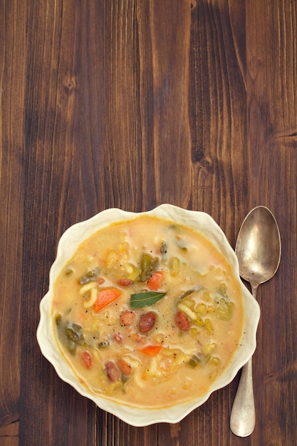 Sopa de legumes com feijão, espinafre e macarrão em tigela branca