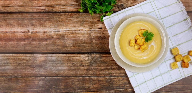 Sopa de legumes cremosa caseira com pão torrado na mesa.