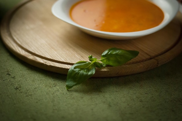 Sopa de legumes e folhas de manjericão em um suporte de madeira