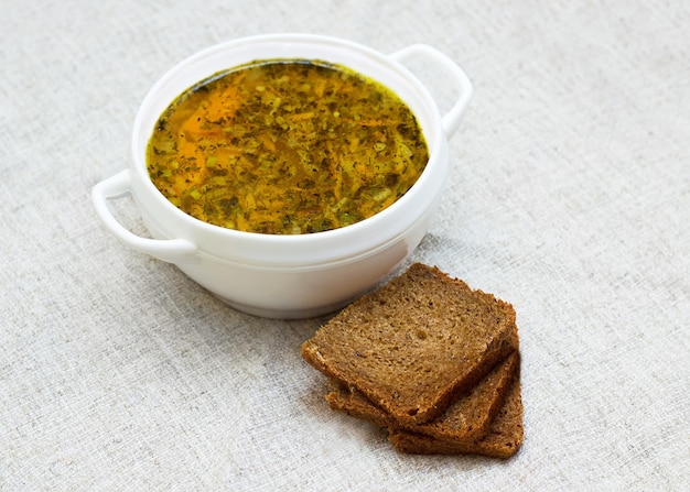 Sopa de legumes e três pedaços de pão na mesa