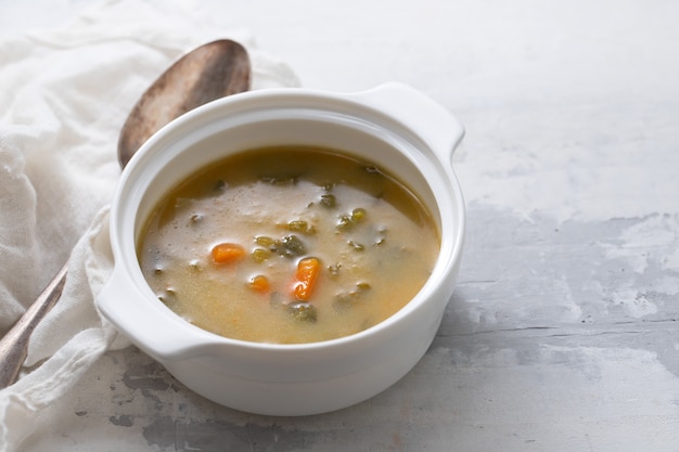 Sopa de legumes em tigela branca sobre cerâmica