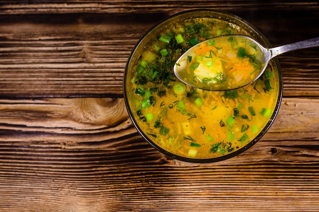 Sopa de legumes em uma tigela de vidro na mesa de madeira Colher com sopa Vista superior