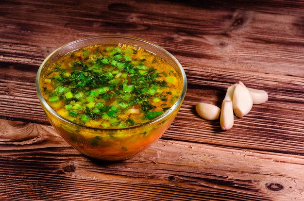 Sopa de legumes em uma tigela de vidro na mesa de madeira