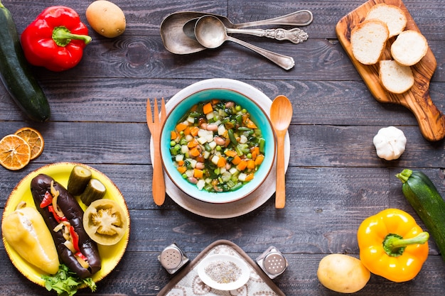 Sopa de legumes fresca, feita em casa, na mesa rústica de madeira, vista superior