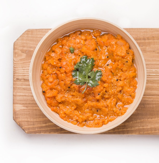 Sopa de lentilha com creme indiano Dhal em um prato sobre uma placa de madeira