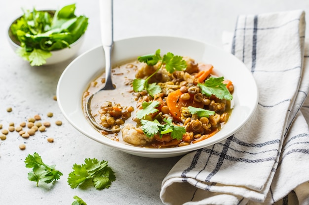 Sopa de lentilha com vegetais em uma placa branca, fundo branco. Alimentos à base de plantas, comer limpo.