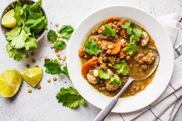 Sopa de lentilha com vegetais em uma placa branca, fundo branco, vista superior. Alimentos à base de plantas, comer limpo.