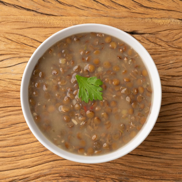 Sopa de lentilha em uma tigela com tempero sobre a mesa de madeira