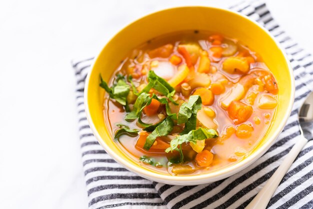 Sopa de lentilha fresca guarnecida com espinafre fresco em uma tigela.