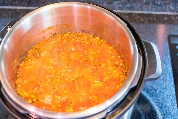 Sopa de lentilha fresca guarnecida com espinafre fresco na panela de pressão.