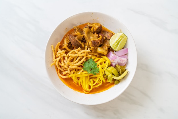 Sopa de macarrão ao curry do norte da tailândia com carne de porco refogada - comida tailandesa