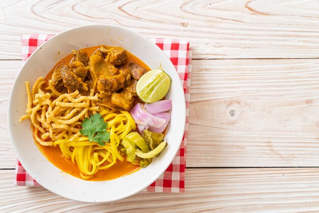 Sopa de macarrão ao curry do norte da Tailândia com carne de porco refogada - comida tailandesa