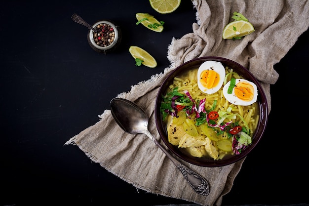 Sopa de macarrão com frango, aipo e ovo em uma tigela em um fundo antigo.