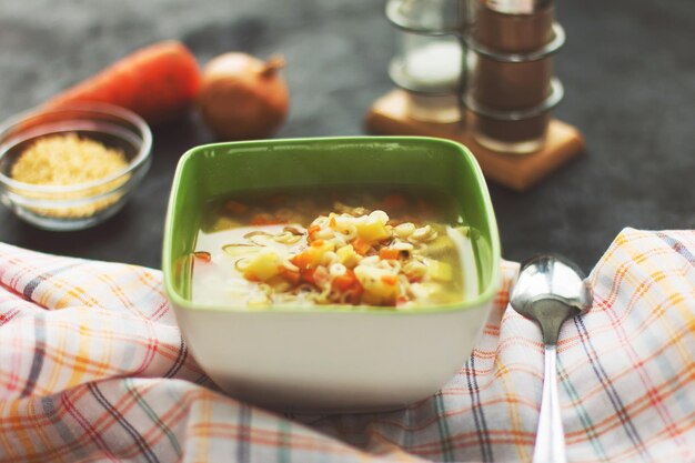 Foto sopa de macarrão de frango com vegetais em uma placa verde com fundo preto