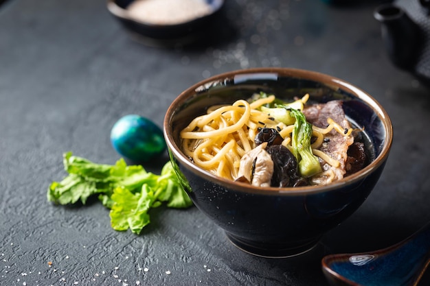 Sopa de macarrão ramen asiático com cogumelos de ostra e legumes em tigela sobre fundo escuro