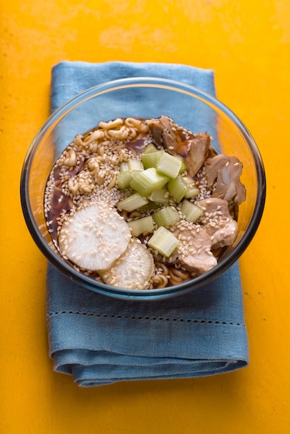 Sopa de macarrão ramen frango aipo em uma vista lateral da mesa amarela