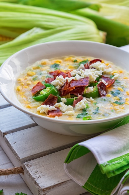 Sopa de milho caseira fresca com bacon, jalapeño e queijo de cabra em tigelas sobre concreto cinza claro