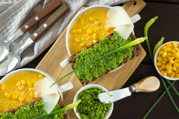 Foto sopa de milho com pasta de alho fresco em tigela branca comida saudável em fundo de madeira preta cozinha vegana