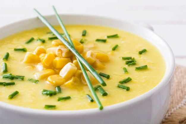 Sopa de milho em uma tigela branca em madeira close-up