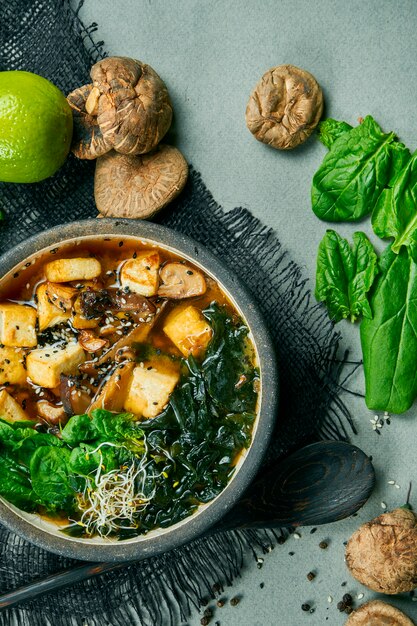 Sopa de miso vegetariana fresca com cogumelos shiitake, queijo tofu e algas em um pano cinza. comida saudável e equilibrada. vista do topo.
