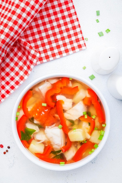 Foto sopa de peixe com truta páprica vermelha batatas tomates e salsa na tigela de sopa de cerâmica na vista superior do fundo da mesa branca